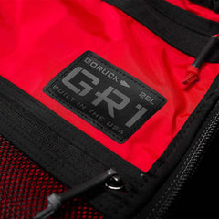 Close-up of red GORUCK GR1 military-style rucksack with black label and durable zipper