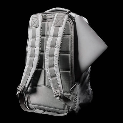 The GR1 USA - Ripstop ROBIC® from GORUCK is displayed from the back, showcasing its sleek, ultra-lightweight design with padded straps. A laptop is visible emerging from one of its water-resistant compartments against a black background.