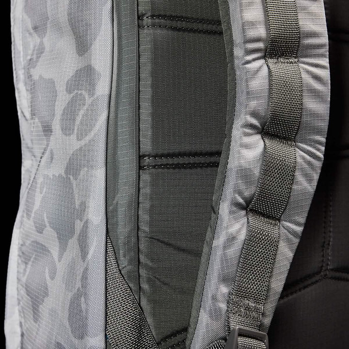 Close-up of the GORUCK GR1 USA - Ripstop ROBIC® backpack featuring a camouflage pattern. The image highlights its padded straps and detailed stitching, showcasing the texture and design of its ultra-lightweight fabric. The colors predominantly include shades of gray and green.
