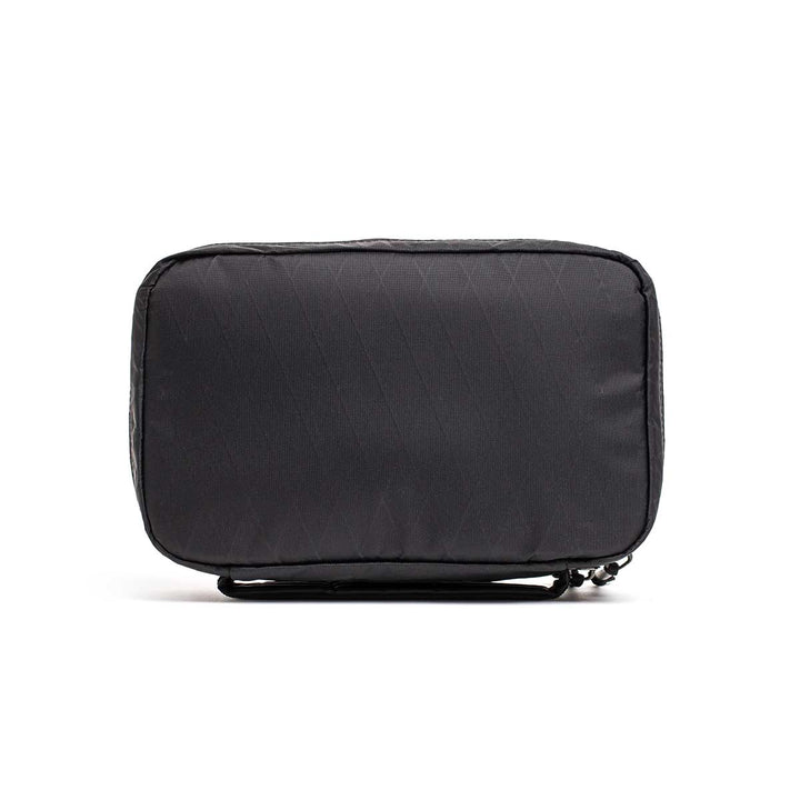 The GR1 Field Pocket - X-PAC is a rectangular black travel pouch with AquaGuard zippers, shown standing upright on a white background—ideal for organizing electronics.