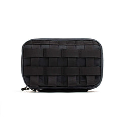 The GR1 Field Pocket - Waxed Canvas is a black rectangular pouch with a woven webbing pattern on the front, made from durable waxed canvas, and shown against a white background.