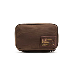 The GR1 Field Pocket is a brown rectangular pouch with a GORUCK patch and zipper, ideal as a dopp kit or for organizing camera gear, shown on a white background.