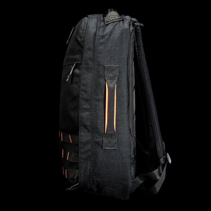 The GR1 Shooter 26L - Built by Scars backpack, featuring orange accents and multiple straps, made from Special Forces Grade CORDURA®, is shown from the side against a black background.