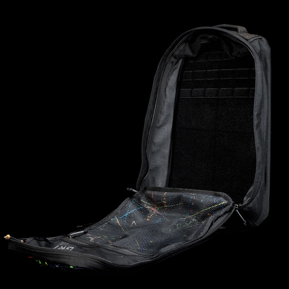 A black GR1 Shooter 26L - Built by Scars backpack, unzipped and open, made from Special Forces Grade CORDURA®, shows a mesh pocket inside the front flap.