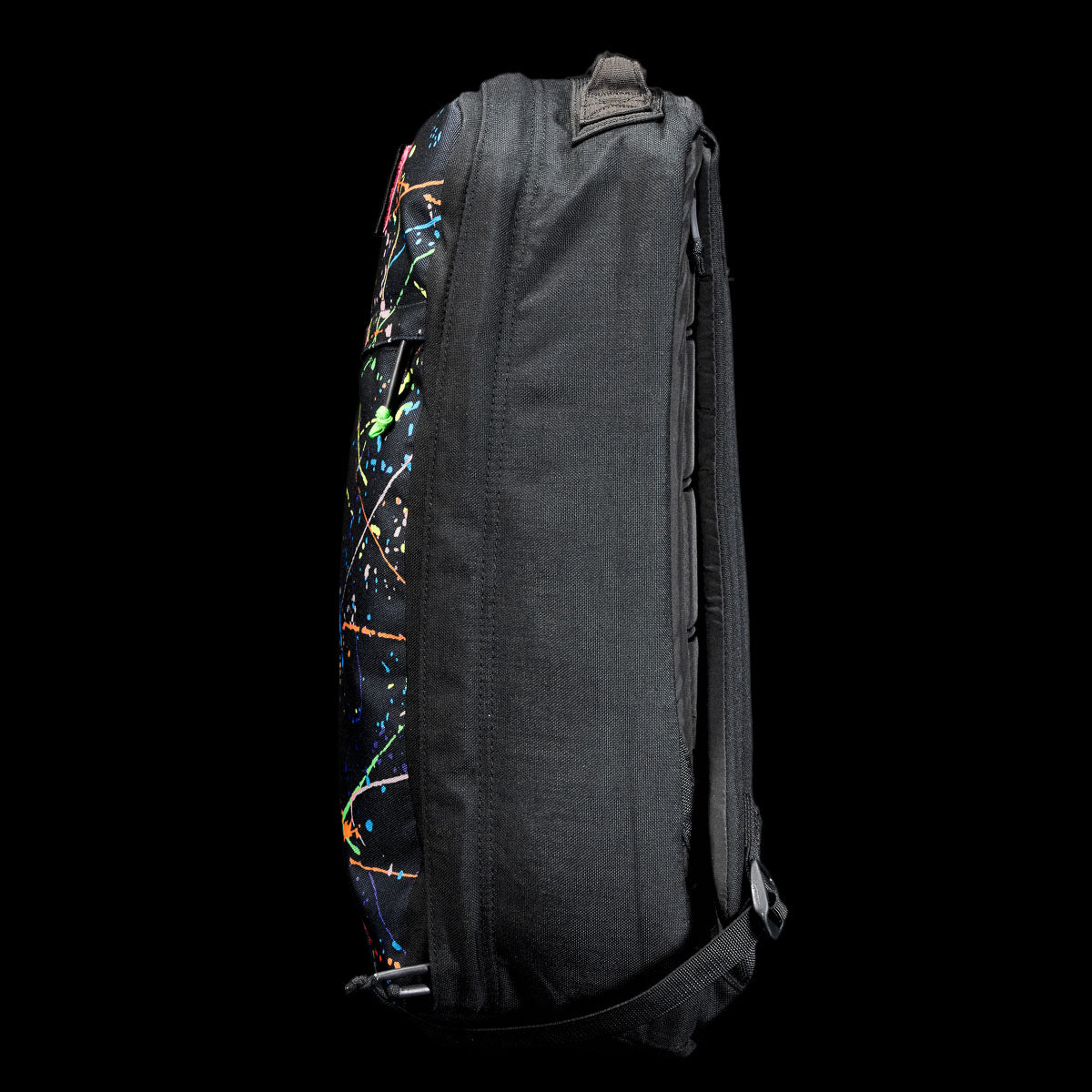 Side view of the GR1 Shooter 26L - Built by Scars, a black backpack made from Special Forces Grade CORDURA®, showcasing a bold paint splatter design on the front.