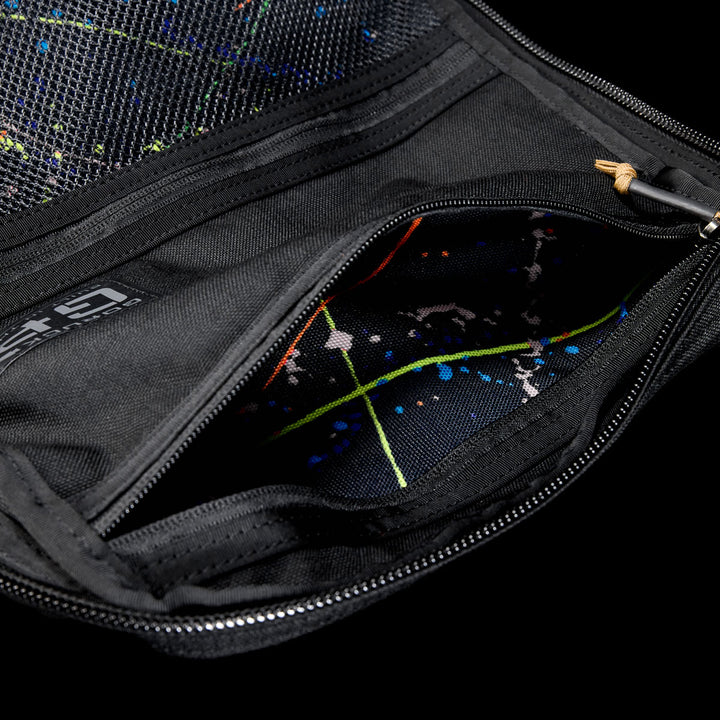 Close-up of an open black GR1 Shooter 26L pouch made from Special Forces Grade CORDURA®, revealing a colorful splatter-patterned lining. Inspired by Shooter Ruck gear and trusted by the SCARS team.