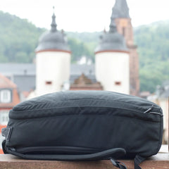 A GR1 USA Slick backpack made from ballistic nylon Cordura sits on a ledge, with historic towers blurred in the background.