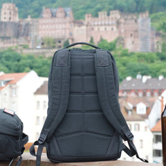 Back view of a sturdy black GORUCK rucking backpack with padded straps on a city rooftop background