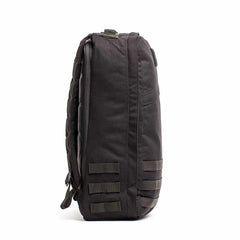 Side view of a black GORUCK durable rucksack with MOLLE webbing and padded back panel on white background