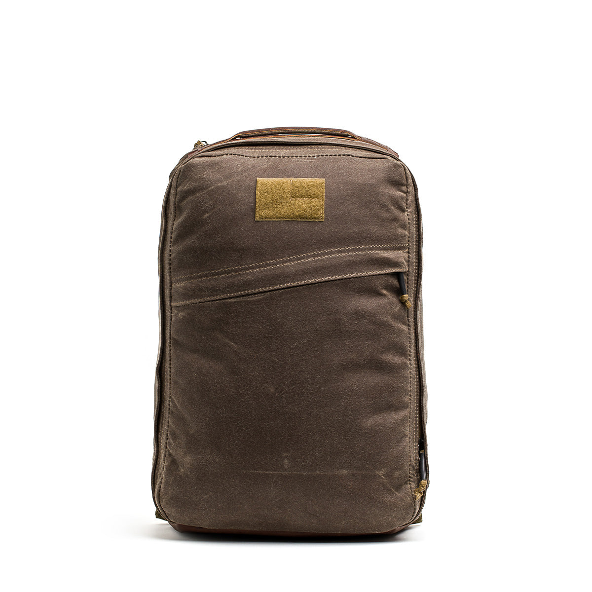 The GR1 USA - Heritage Waxed Canvas is a brown rucksack with a rectangular tan patch, shown upright on a white background—crafted for durability and lasting performance.
