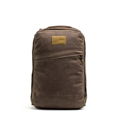 The GR1 USA - Heritage Waxed Canvas is a brown rucksack with a rectangular tan patch, shown upright on a white background—crafted for durability and lasting performance.
