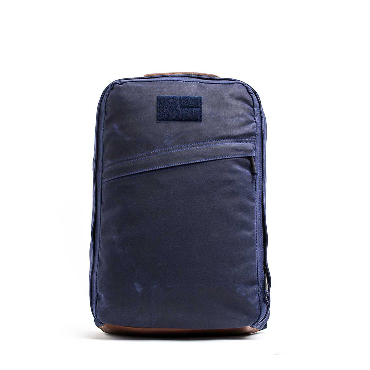 The GR1 USA - Heritage Waxed Canvas backpack in navy blue features a front zipper pocket and is displayed upright against a white background.
