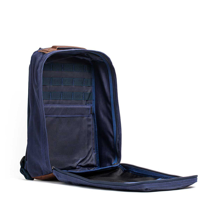 Open the GR1 USA - Heritage backpack in navy blue with a retro canvas rucksack style, showcasing a bombproof laptop compartment and mesh pockets, displayed on a white background.