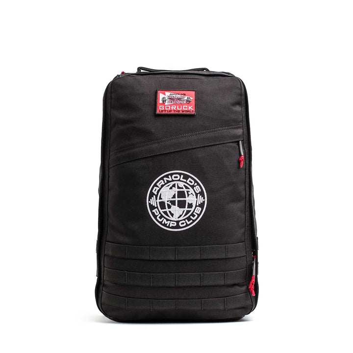 The 26L GR1 USA - GORUCK x Arnold's Pump Club features a black design with red zippers, a GORUCK patch, and the "Arnold's Pump Club" globe logo on the front. This limited-edition backpack is proudly built in the USA.