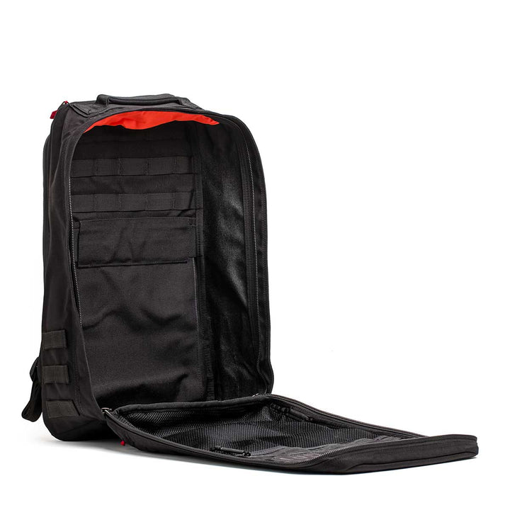 The 26L GR1 USA - GORUCK x Arnold's Pump Club black limited-edition backpack is shown with its main compartment fully unzipped, revealing interior pockets and mesh sections.