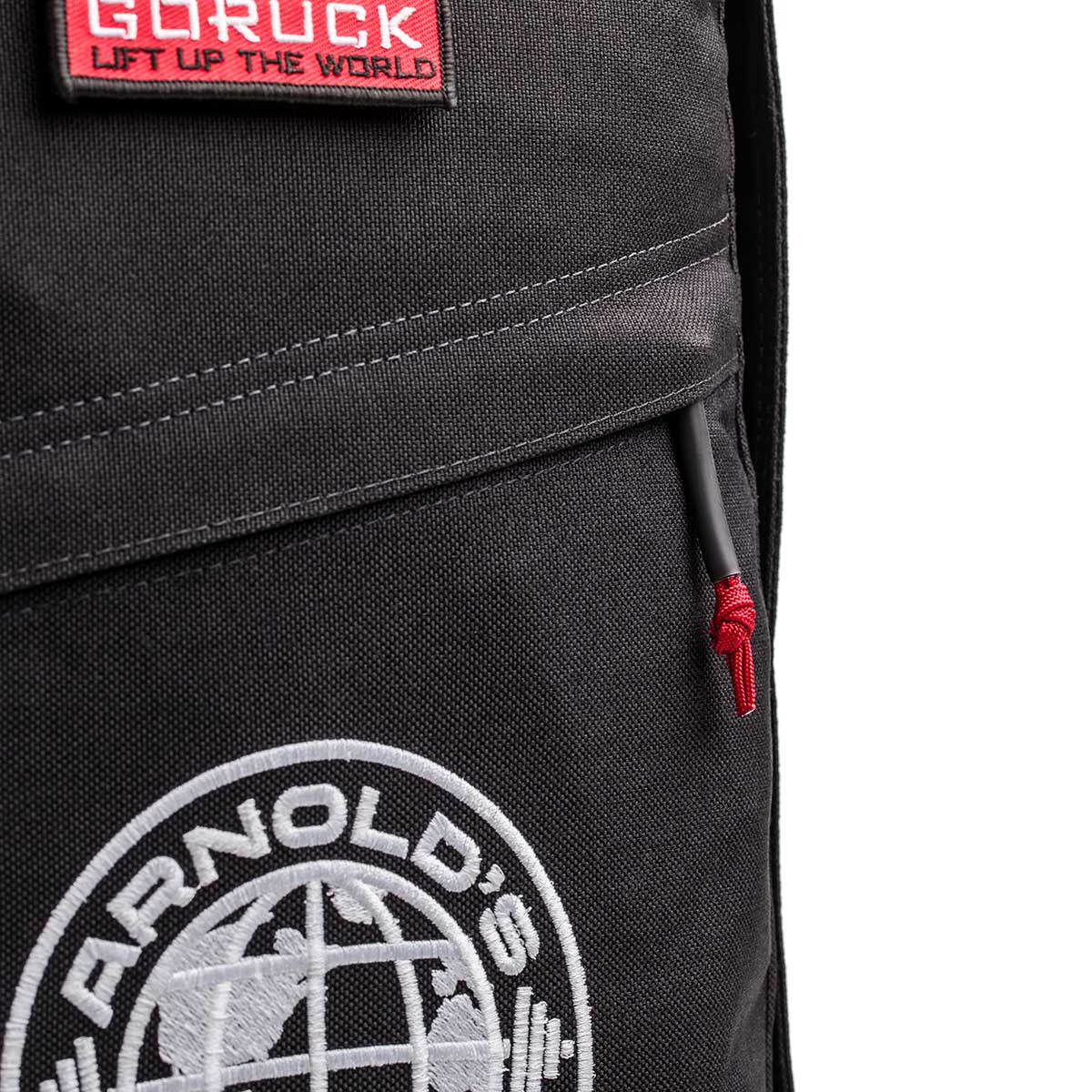Close-up of the 26L GR1 USA - GORUCK x Arnold's Pump Club rucksack, showcasing "GORUCK" and "ARNOLD'S" patches, a red zipper pull, and signature USA-made durability.