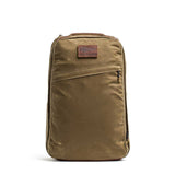 The GR1 USA - Heritage Waxed Canvas backpack features a khaki color, front zippered pocket, and a brown patch label on the top front.