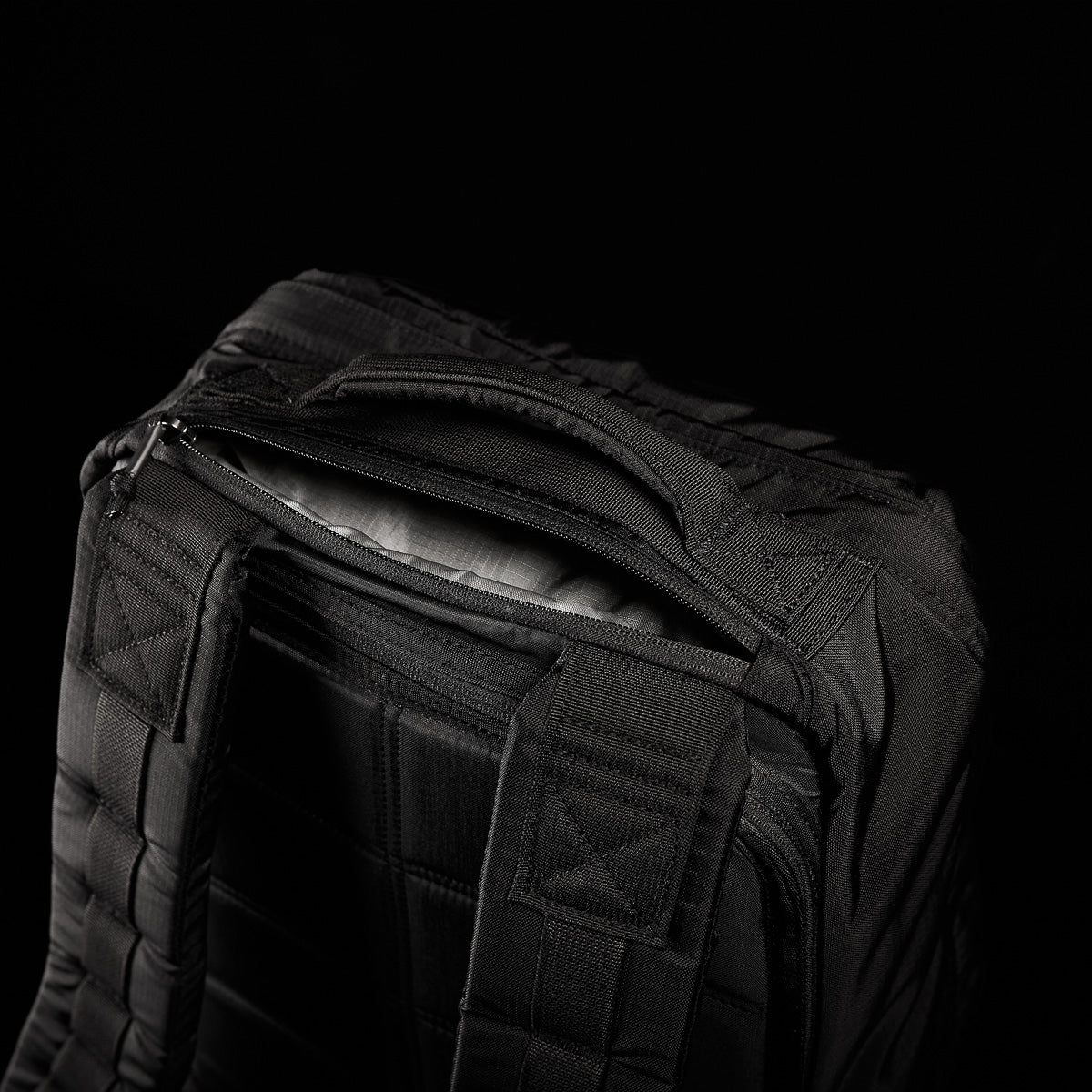 The GR1 USA - Ripstop ROBIC® is a black tactical backpack made from ultra-lightweight 420D Robic® Ripstop Nylon, featuring a rugged handle and stitching against a dark background.
