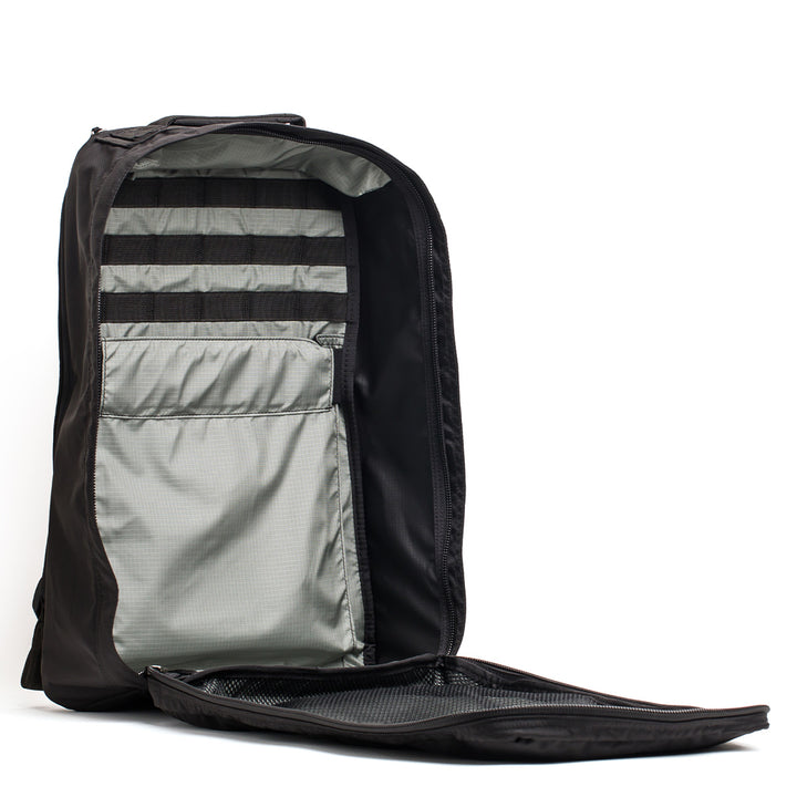 The GR1 USA - Ripstop ROBIC® black backpack, made from ultra lightweight 420D Robic Ripstop Nylon, reveals internal pockets and straps for organization when the front compartment is unzipped.