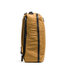 Side view of coyote brown GORUCK GR1 26L rucksack with black zippers on white background