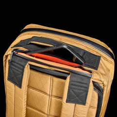 GORUCK GR1 26L backpack in coyote with padded back and zipped pocket holding a smartphone