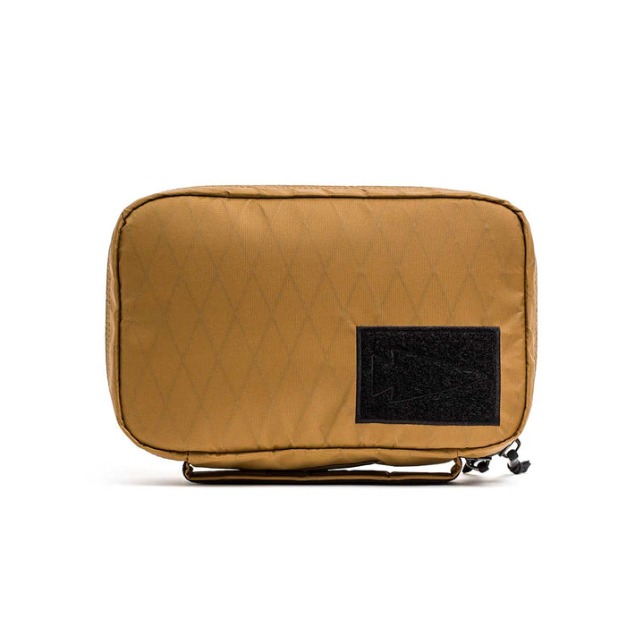 The GR1 Field Pocket - X-PAC is a tan rectangular pouch with a black front patch, made from waterproof X-PAC fabric, shown against a white background.