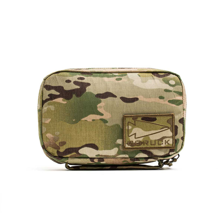 The GR1 Field Pocket - X-PAC is a compact, camouflage pouch made of waterproof X-PAC fabric, featuring a mountain patch with "GORUCK" text.