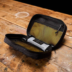 Open black GORUCK tactical organizer with yellow mesh pockets on wooden surface