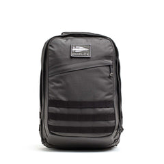 A black GR2 - Cordura ruck backpack with a front zipper pocket and horizontal webbing straps, designed for carry-on travel, is shown on a white background.