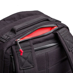 Close-up of the GR2 - Cordura travel backpack in black, with a partially open zipper exposing a bright red interior pocket.