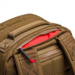 Close-up of the GR2 - Cordura in brown with a partially open zipper, showing its bright red interior pocket—ideal for anyone seeking a Special Forces-grade backpack or a dependable carry-on travel bag.