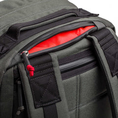 A close-up of the gray GR2 - Cordura backpack, featuring black zippers and a red interior, partially unzipped at the top.