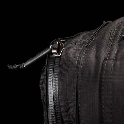 Close-up of the GR2 - Ripstop ROBIC® travel bag by GORUCK, featuring a slightly open zipper with a black cord attached to the pull. The fabric texture and stitching stand out against the dark background, emphasizing its water-resistant design.