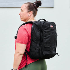 Woman wearing black GORUCK backpack outdoors, showcasing durable rucking gear