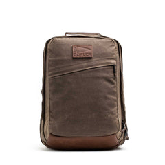 The GR2 - Heritage Waxed Canvas is a brown waxed canvas backpack with a leather bottom and diagonal front zipper pocket, ideal as a travel ruck for daily adventures.