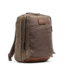 The GR2 - Heritage Waxed Canvas is a brown backpack with leather accents, side zipper pockets, and a top handle, ideal for travel ruck use and shown against a white background.