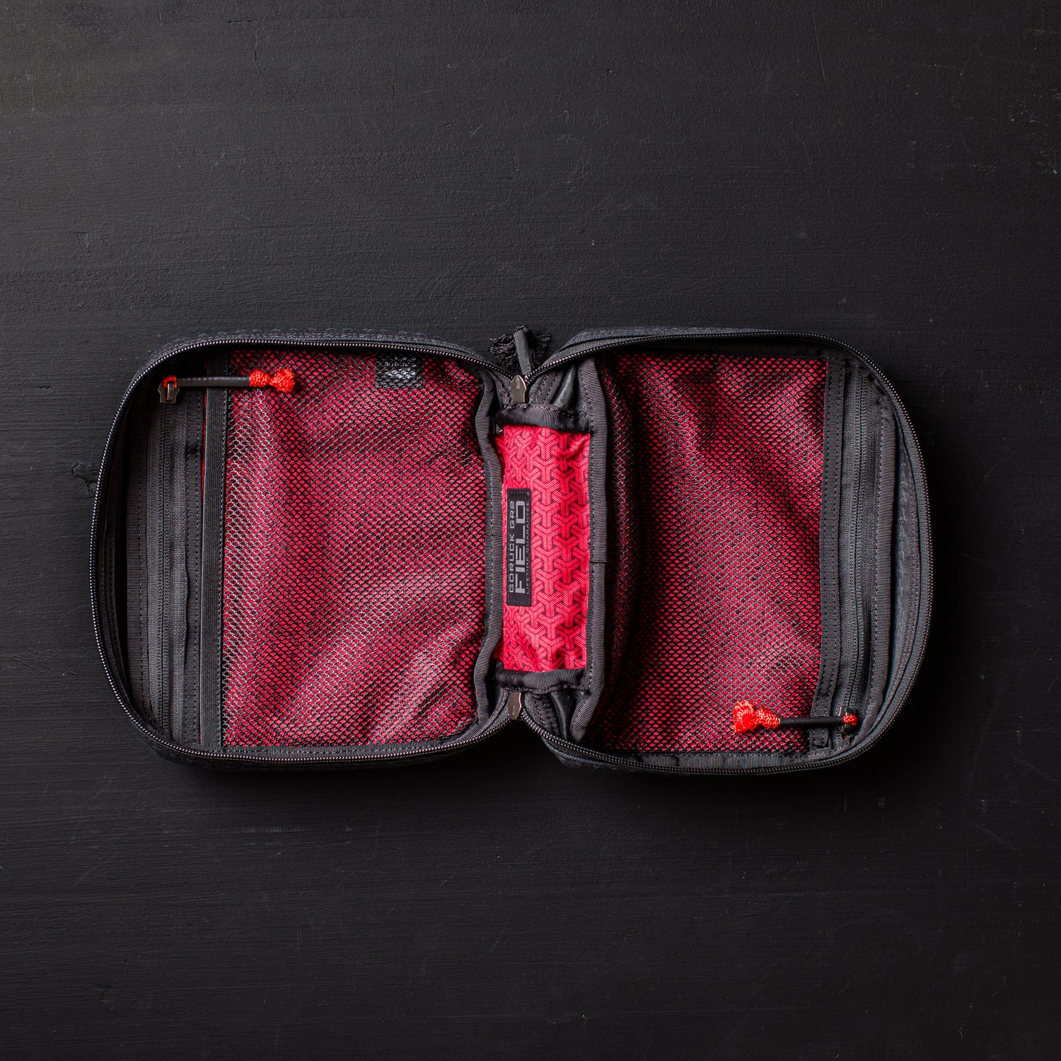 An open GR2 Field Pocket - GRXC2 Samurai 2.0, crafted from JPXDP fabric in black and red with mesh pockets and a zippered design, lies on a black surface.