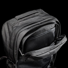 Close-up of black GORUCK rucksack with open front zipper pocket and mesh organizer on black background