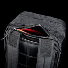 Close-up of GORUCK black rugged backpack top with a smartphone partially inside zippered compartment