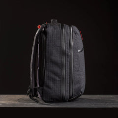Side view of black GORUCK GR2 26L Samurai 2.0 rucksack with textured fabric and dual zippers on dark background