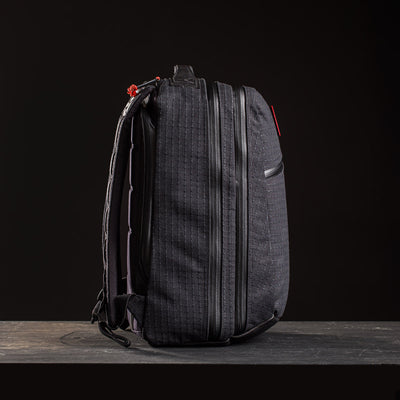The GR2 x Carryology - GRXC2 Samurai 2.0 backpack stands upright against a dark background, showcasing textured black fabric, zippers, red accents, and signature Black Samurai Sashiko details.