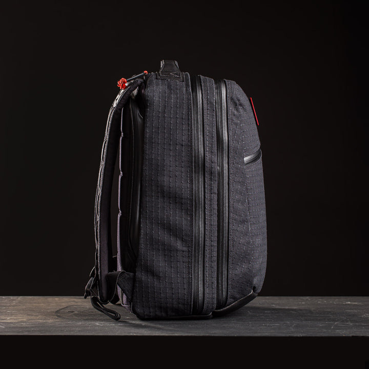 The GR2 x Carryology - GRXC2 Samurai 2.0 backpack stands upright against a dark background, showcasing textured black fabric, zippers, red accents, and signature Black Samurai Sashiko details.