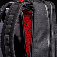 Close-up of black GORUCK GR2 26L backpack showing padded straps and red geometric interior lining