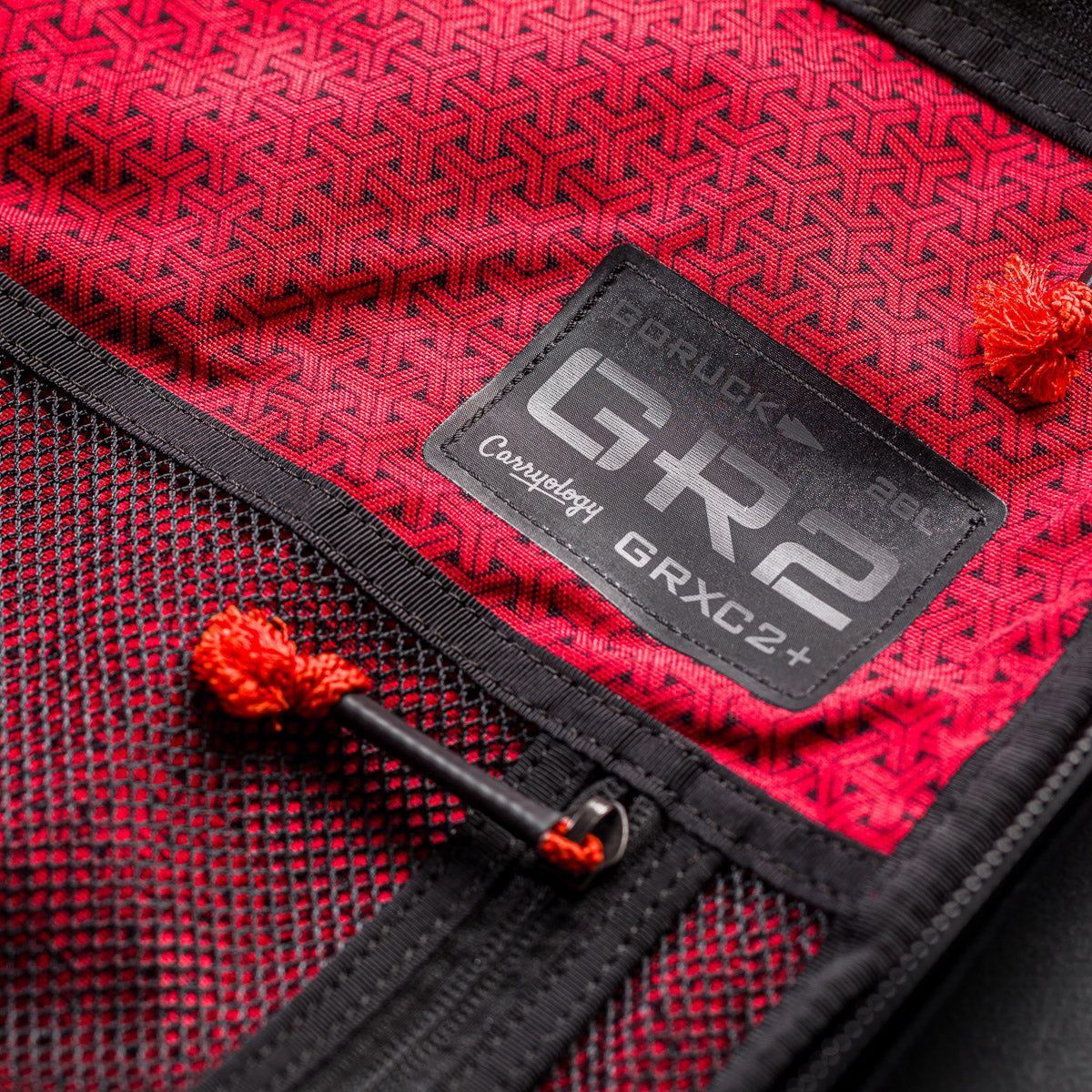 Close-up of a red fabric backpack interior with black mesh pocket and "GR2" patch, from the GR2 x Carryology - GRXC2 Samurai 2.0 collaboration.