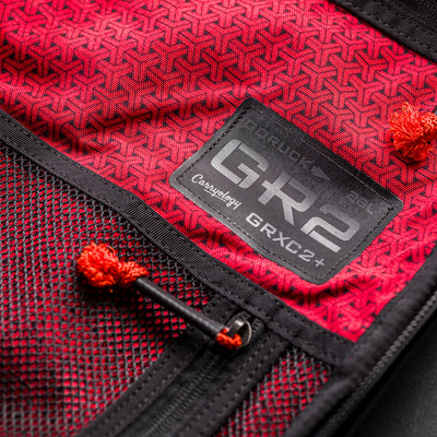Close-up of a red fabric backpack interior with black mesh pocket and "GR2" patch, from the GR2 x Carryology - GRXC2 Samurai 2.0 collaboration.