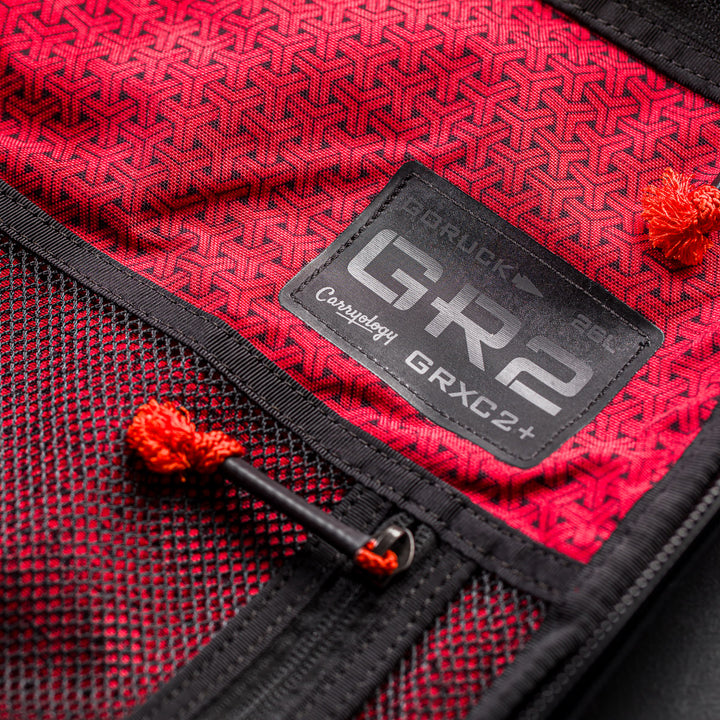 Close-up of a red fabric backpack interior with black mesh pocket and "GR2" patch, from the GR2 x Carryology - GRXC2 Samurai 2.0 collaboration.