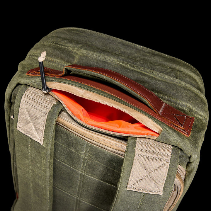 The GR2 - Waxed Canvas backpack features green waxed canvas, tan straps, an orange interior, and a partially open top zipper—ideal for travel—displayed against a black background.