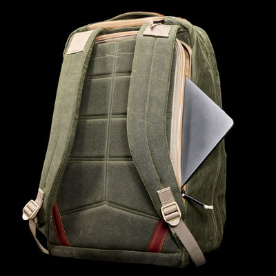 GR2 - Waxed Canvas travel ruck in green features padded straps and a side zipper pocket with a partially visible laptop, crafted from durable duck canvas, shown on a black background.
