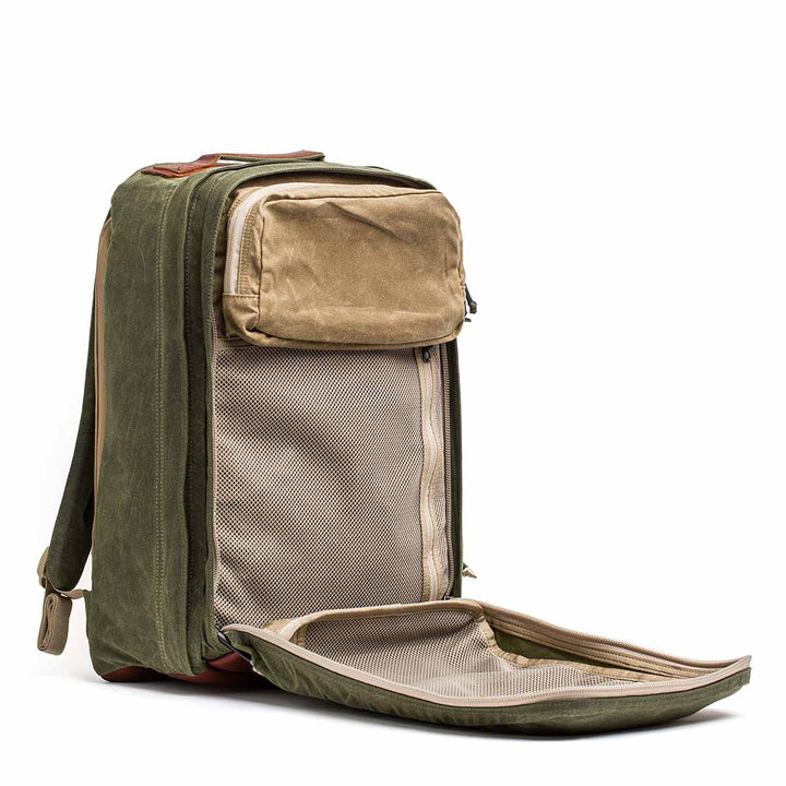 The GR2 - Waxed Canvas features durable construction in green with tan accents, plus a front compartment that unzips to reveal an internal mesh pocket and ample storage space.