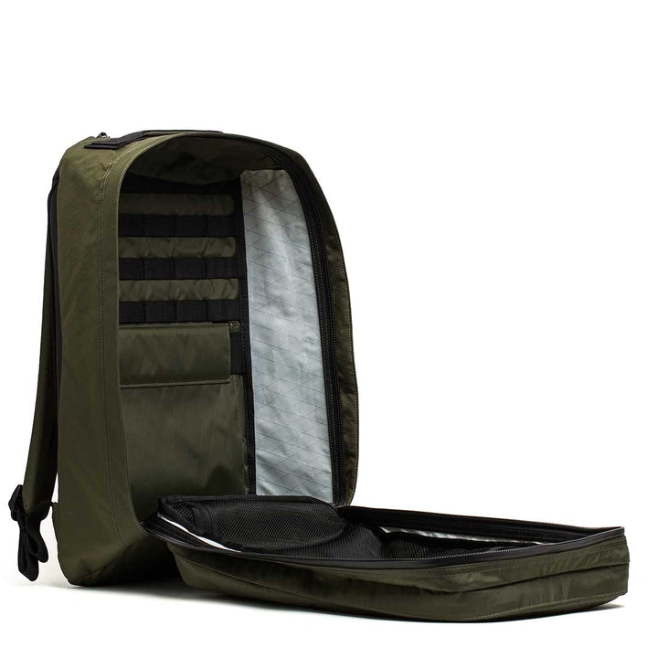 The GR2 X-PAC backpack in olive green features a padded back panel, interior pockets, mesh compartment, and AquaGuard zippers for waterproof protection when unzipped.